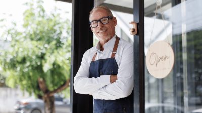 Small business owner smiling in the doorway of his shop
