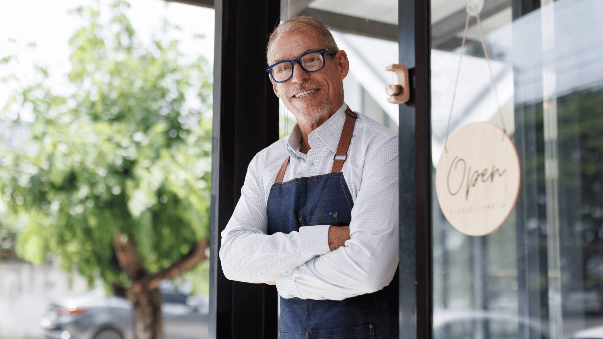 Small business owner smiling in the doorway of his shop