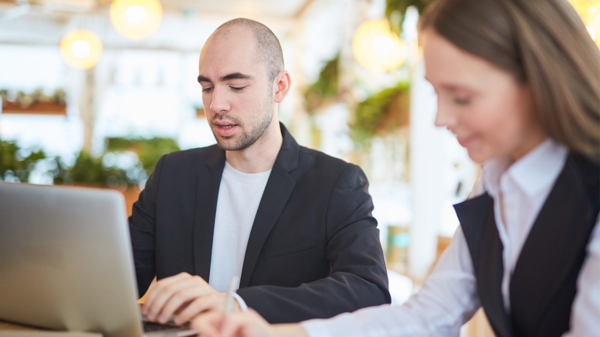 Two coworkers reviewing documents together at a laptop in an office